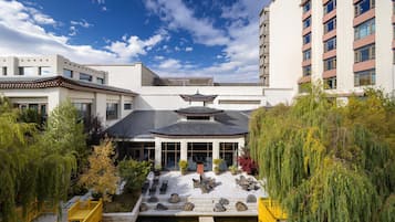 Un edificio de estilo tradicional con una estructura parecida a una pagoda, rodeado de exuberante vegetación y un pequeño estanque.