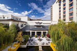 A traditional-style building with a pagoda-like structure, surrounded by lush greenery and a small pond. - Shangri-La Resort, Shangri-La (Deqin)