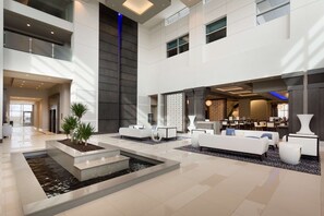 A spacious lobby with a central water feature, modern seating, and a reception area. - Embassy Suites by Hilton Kansas City Olathe (Olathe)