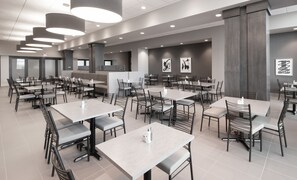 A spacious restaurant with multiple tables and chairs, recessed lighting, and artwork on the walls. - Embassy Suites by Hilton Kansas City Olathe (Olathe)