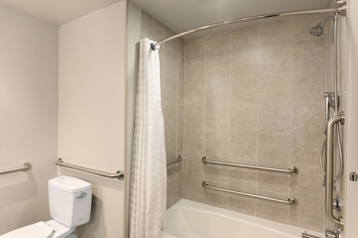 Une salle de bain équipée d’une douche, de toilettes et de barres d’appui.
