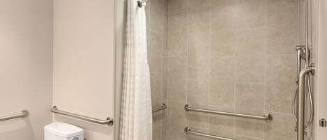 A bathroom with a shower, toilet, and grab bars.