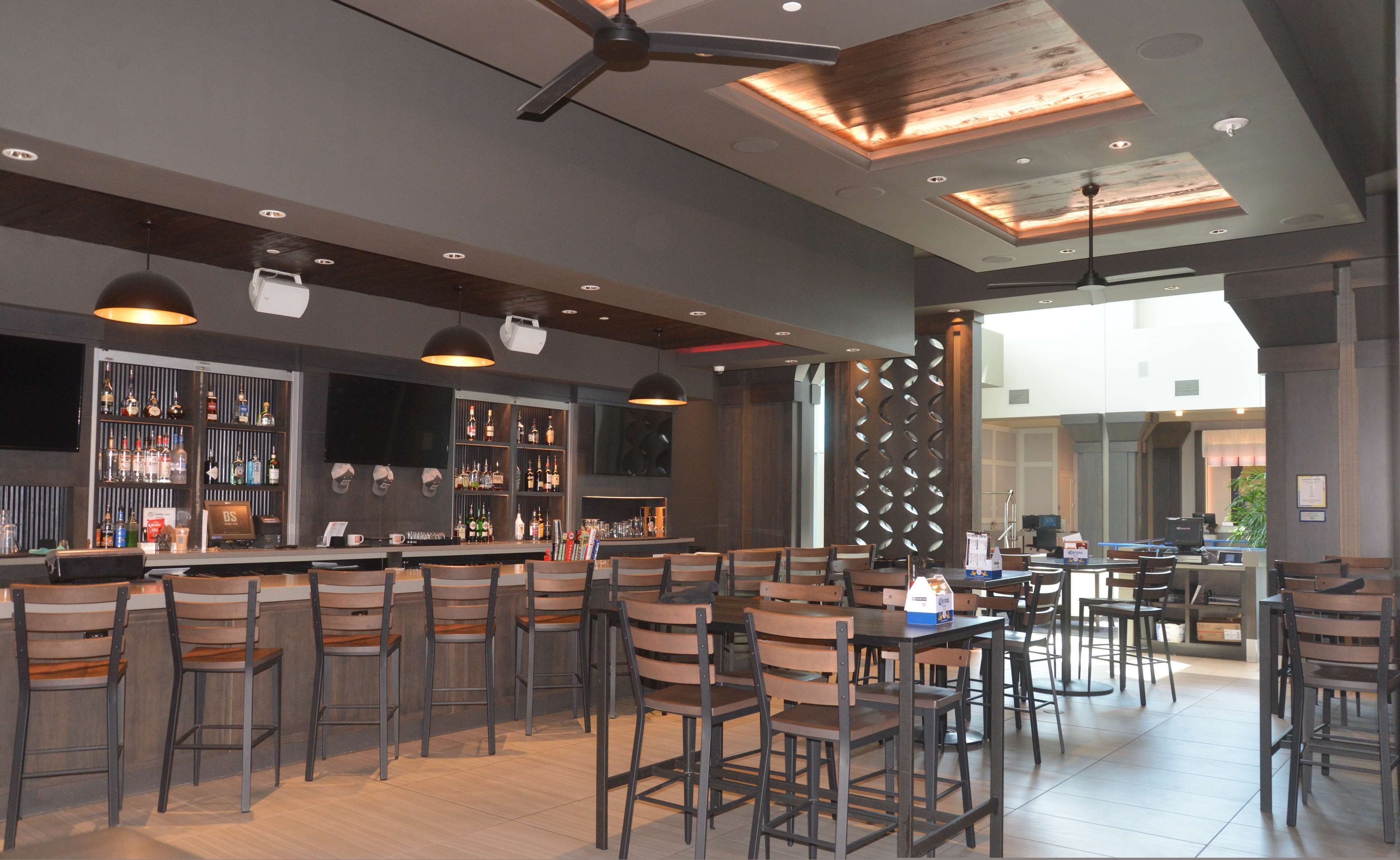 A bar area with multiple seating options, a bar counter with various bottles, and a ceiling fan.