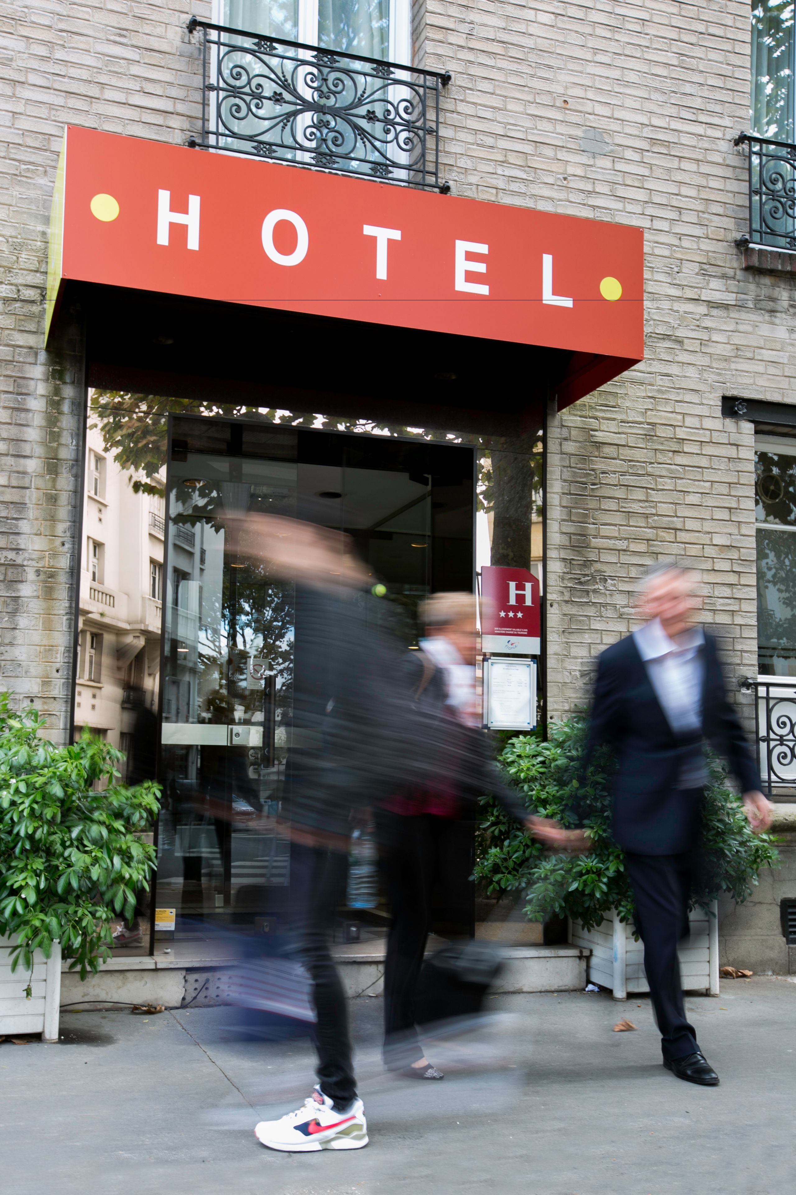Entrada de un hotel con un letrero llamativo que dice "HOTEL" y un toldo rojo.