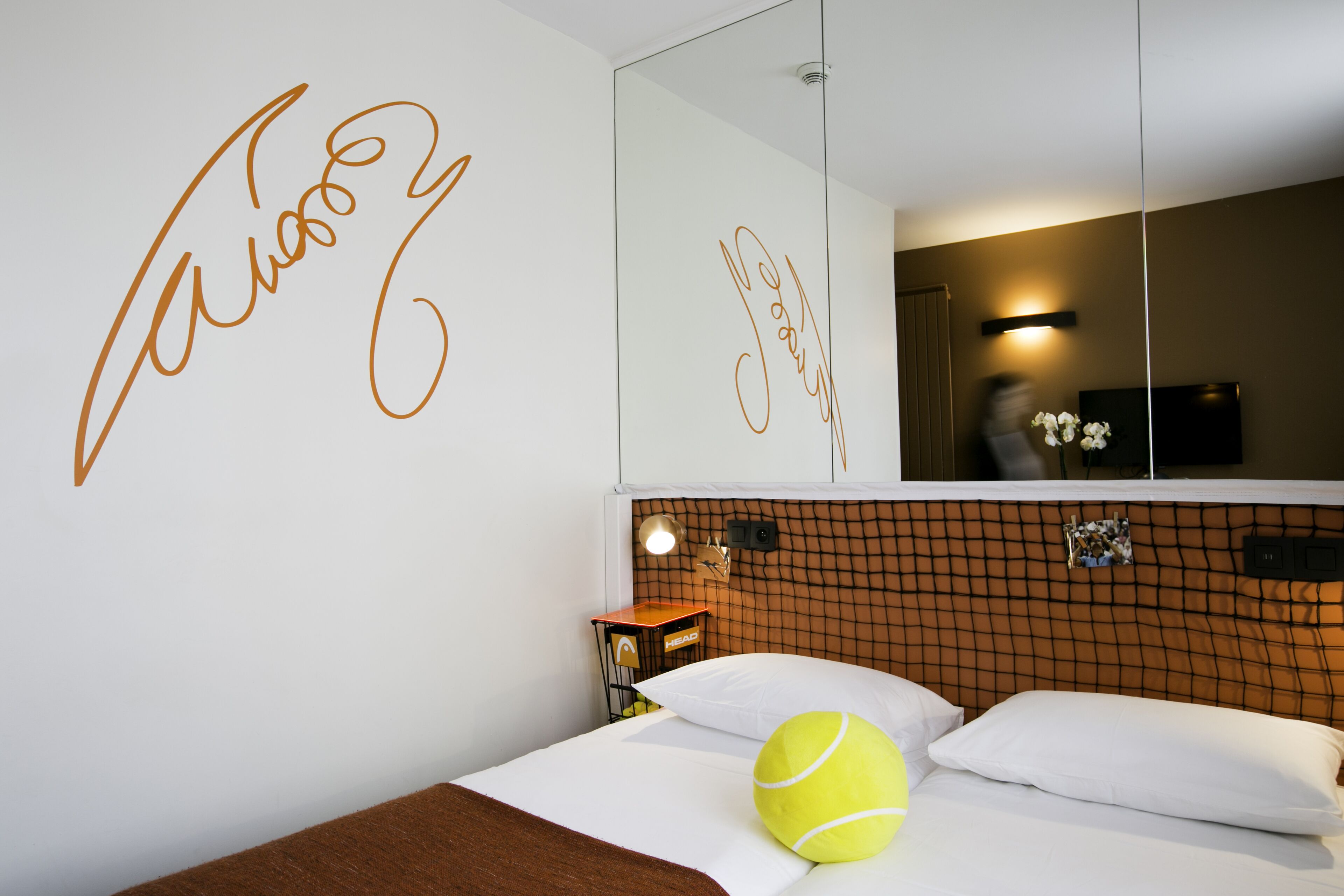Ein Hotelzimmer mit einem Bett, einem Spiegel und einer Wand, auf der ein Name in Schreibschrift steht.
