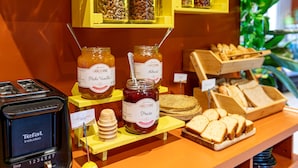 A display of various food items including jars of jam, honey, and bread. - Hotel Olympic Paris Boulogne by Patrick Hayat (Boulogne-Billancourt)