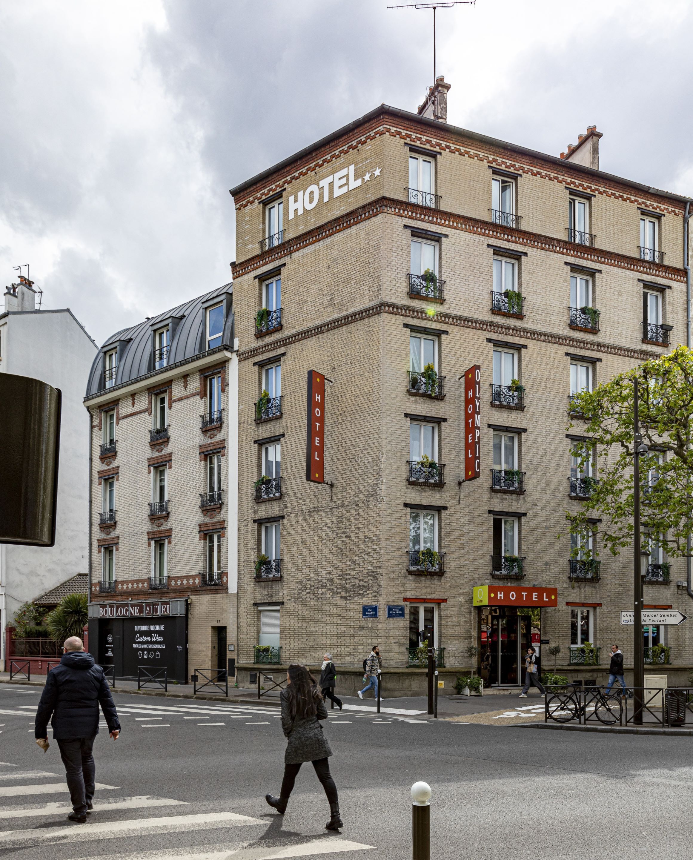 A hotel building with multiple floors, balconies with plants, and a sign indicating it is a hotel.
