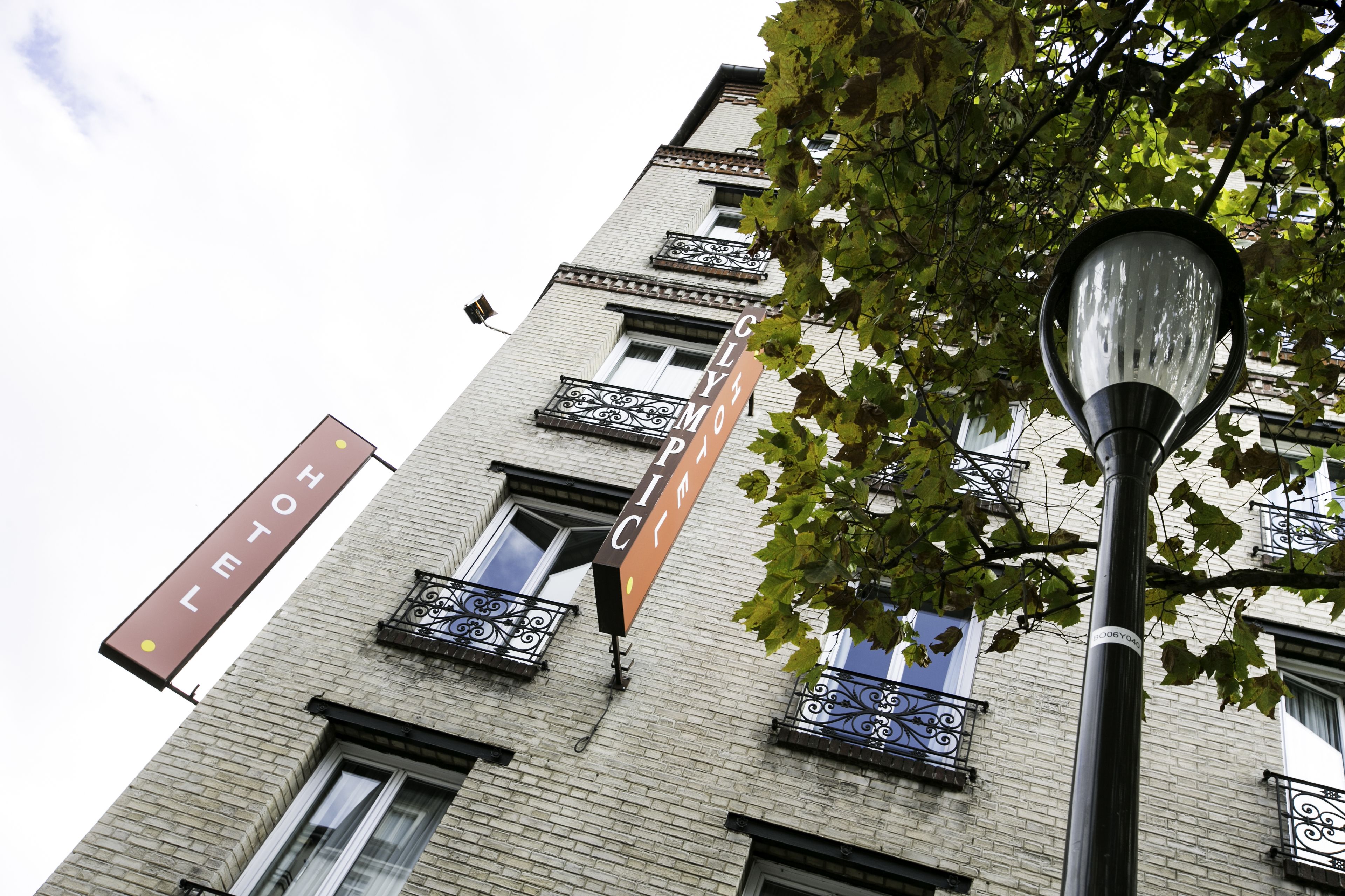 A building with multiple windows and balconies, a street lamp, and hanging signs.
