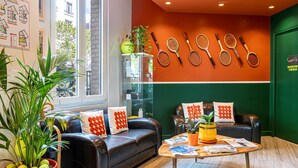 A modern living room with a leather sofa, a coffee table, and a wall adorned with tennis rackets. - Hotel Olympic Paris Boulogne by Patrick Hayat (Boulogne-Billancourt)