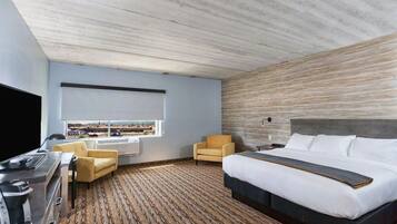 Une chambre d’hôtel moderne dotée d’un grand lit, d’un téléviseur à écran plat, d’un bureau avec une machine à café et offrant une vue sur la ville par la fenêtre.
