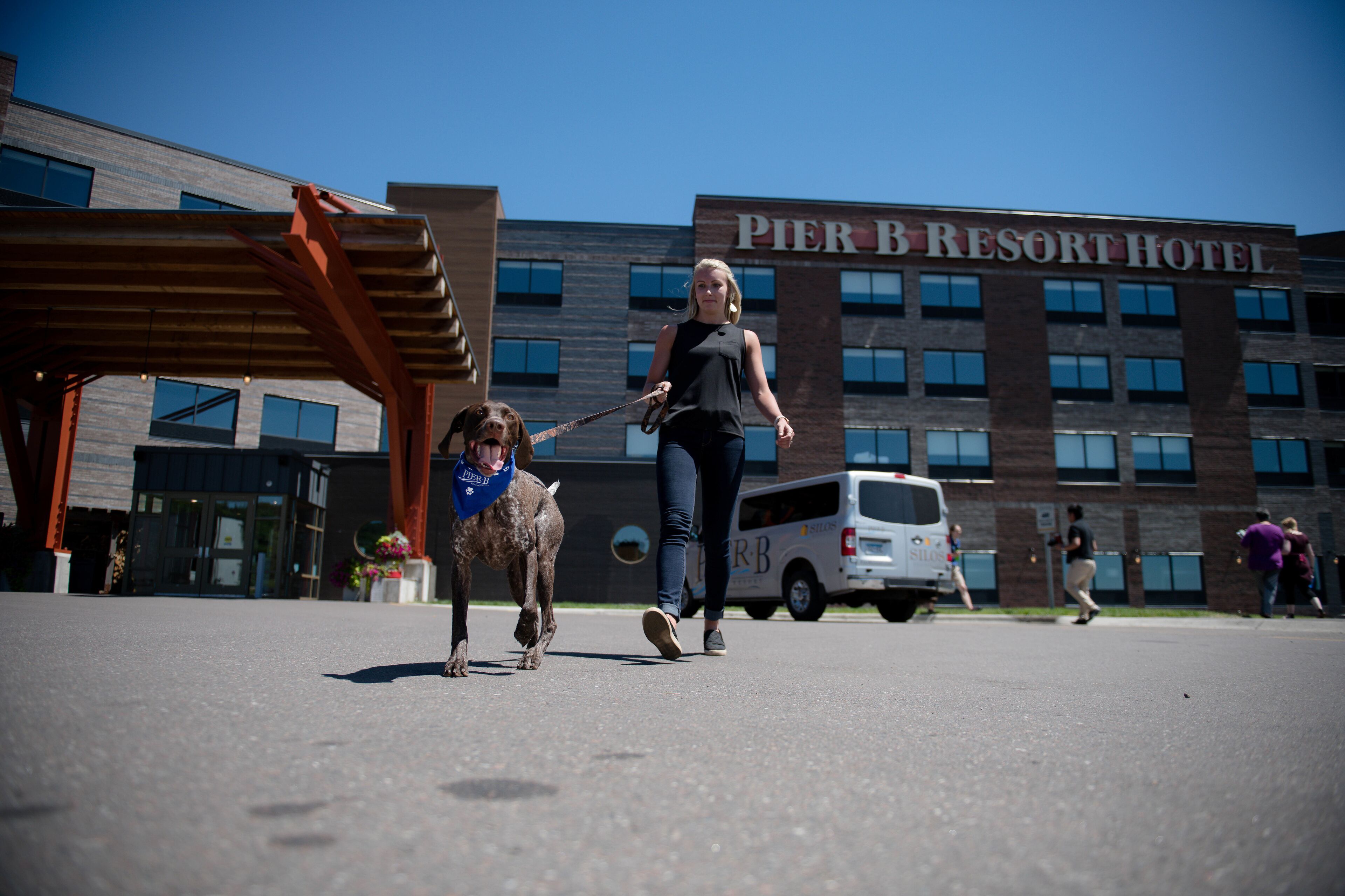 Une femme promène un chien devant l’hôtel Pier B Resort.