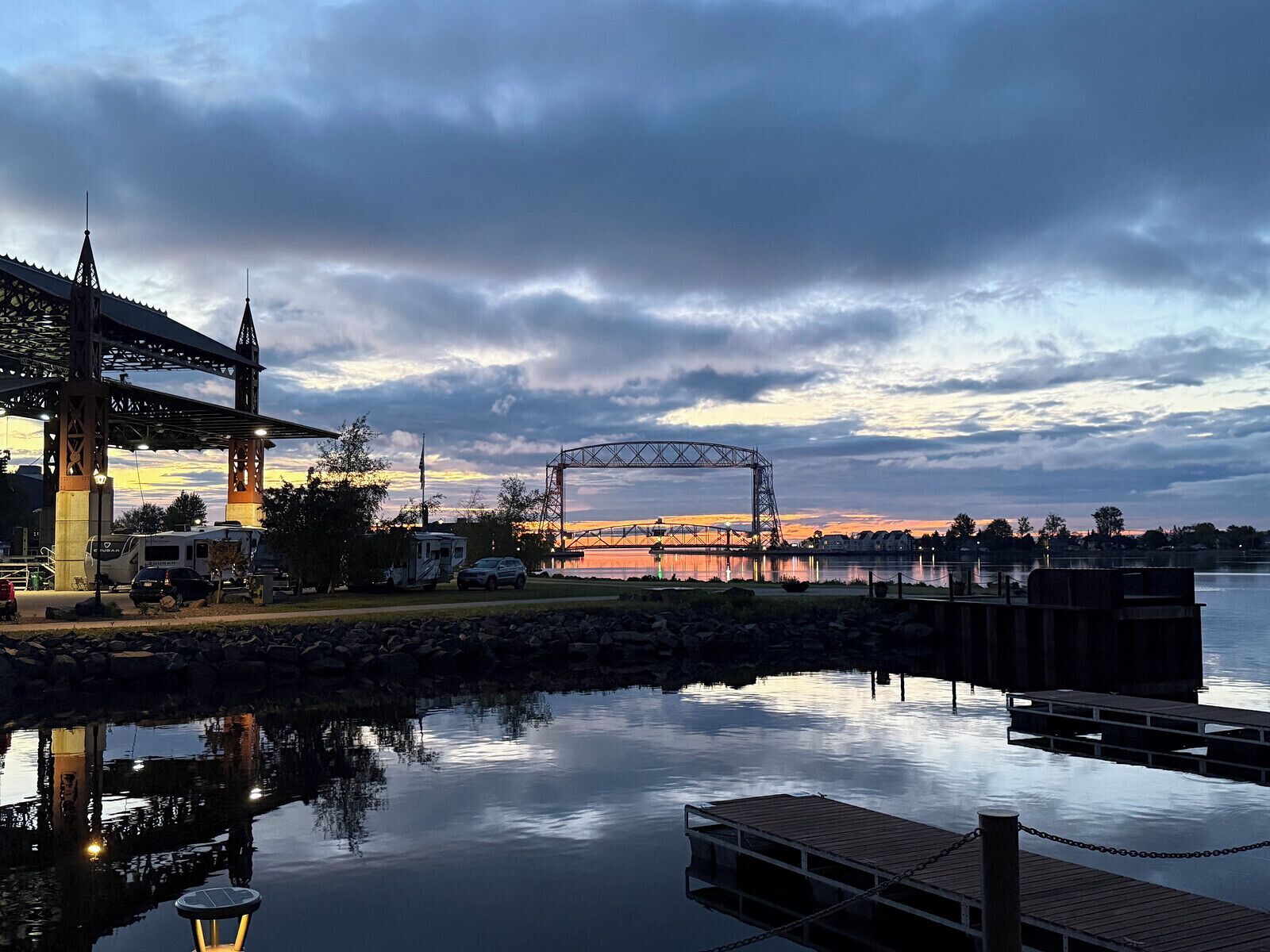 Vista al frente del agua con un puente, un muelle y una zona para vehículos recreativos.