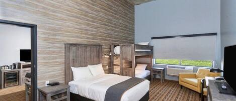 A modern hotel room with a large bed, a desk, a chair, and a view of the outdoors.