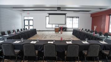 A conference room with a long table, chairs, a projector screen, and a podium.