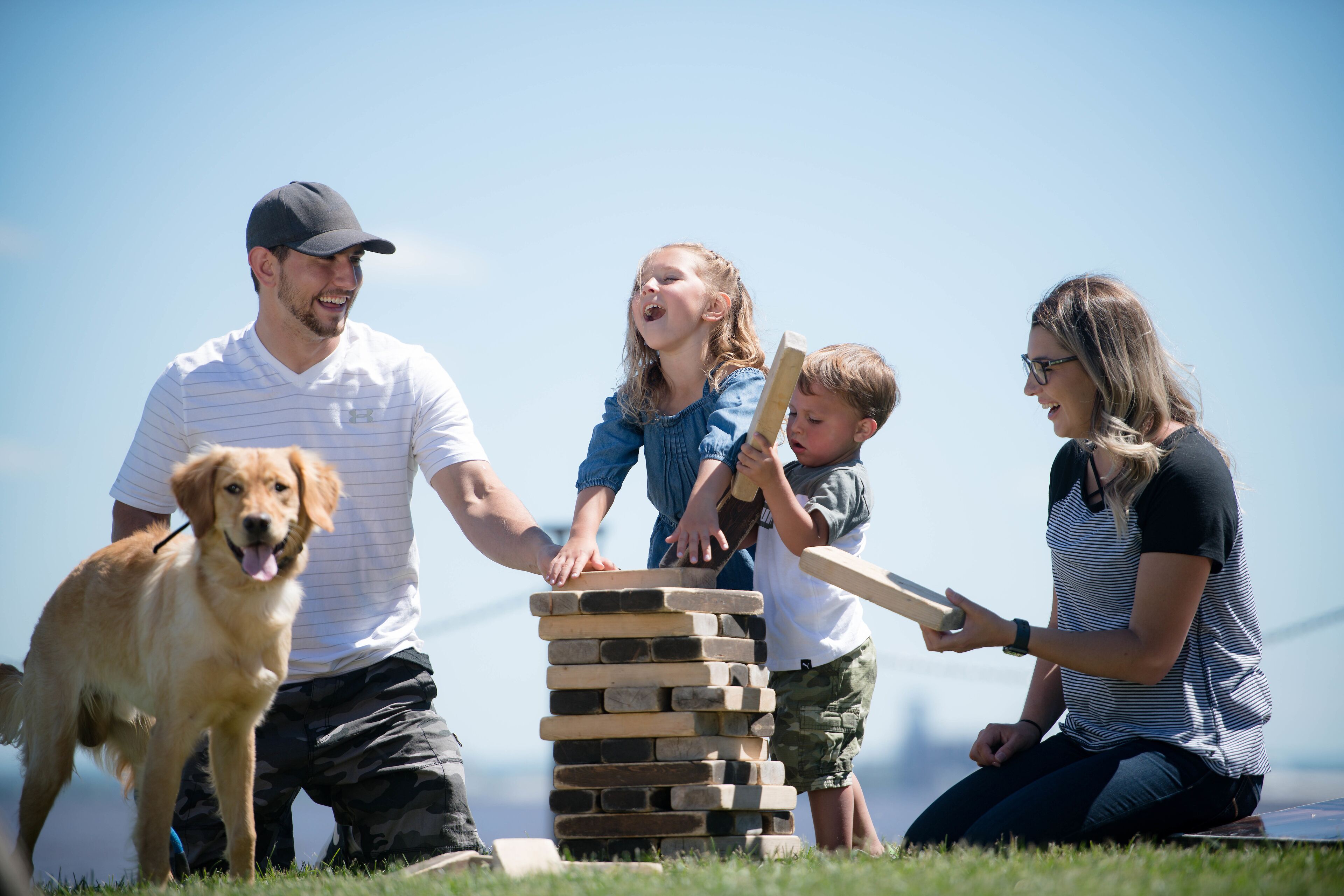 A family playing a game outdoors with a dog nearby.