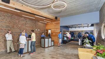 A reception area with a brick wall, wooden ceiling, and a clothing store in the background.