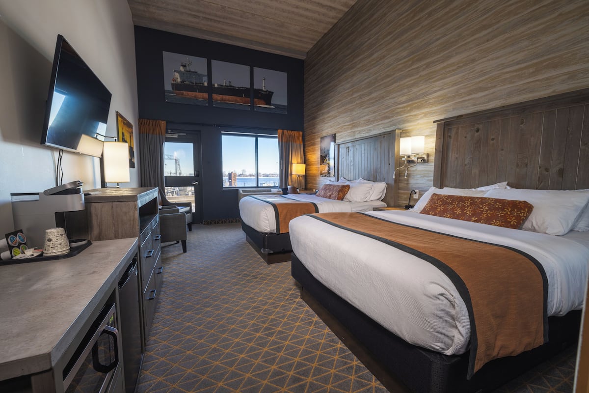 Une chambre d’hôtel avec deux lits, une télévision, un bureau et une vue sur le port.
