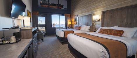 Habitación de hotel con dos camas, televisión, escritorio y vista al puerto.