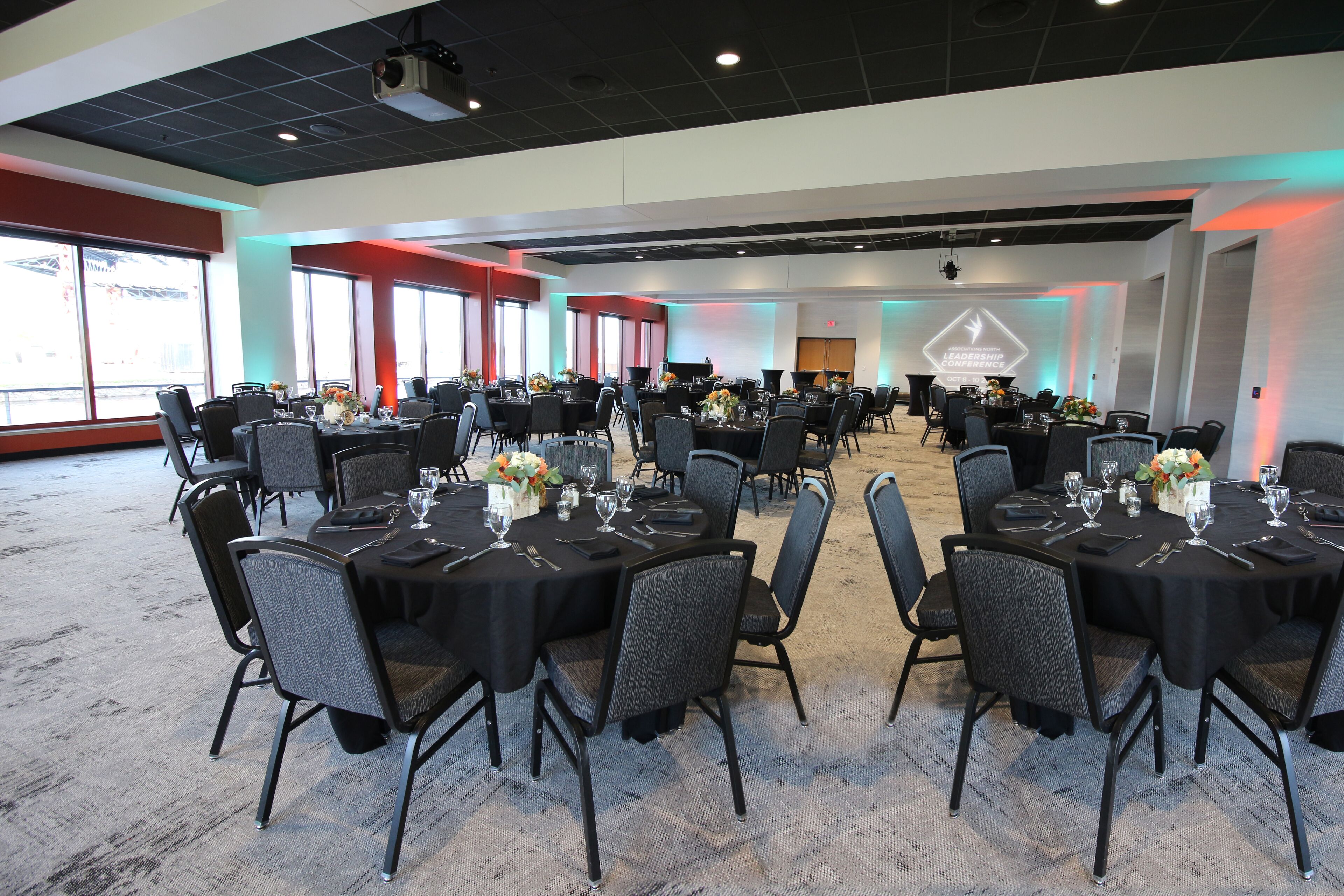 A conference room with multiple tables set for dining, equipped with chairs and table settings.