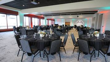 A conference room with multiple tables set for dining, equipped with chairs and table settings.