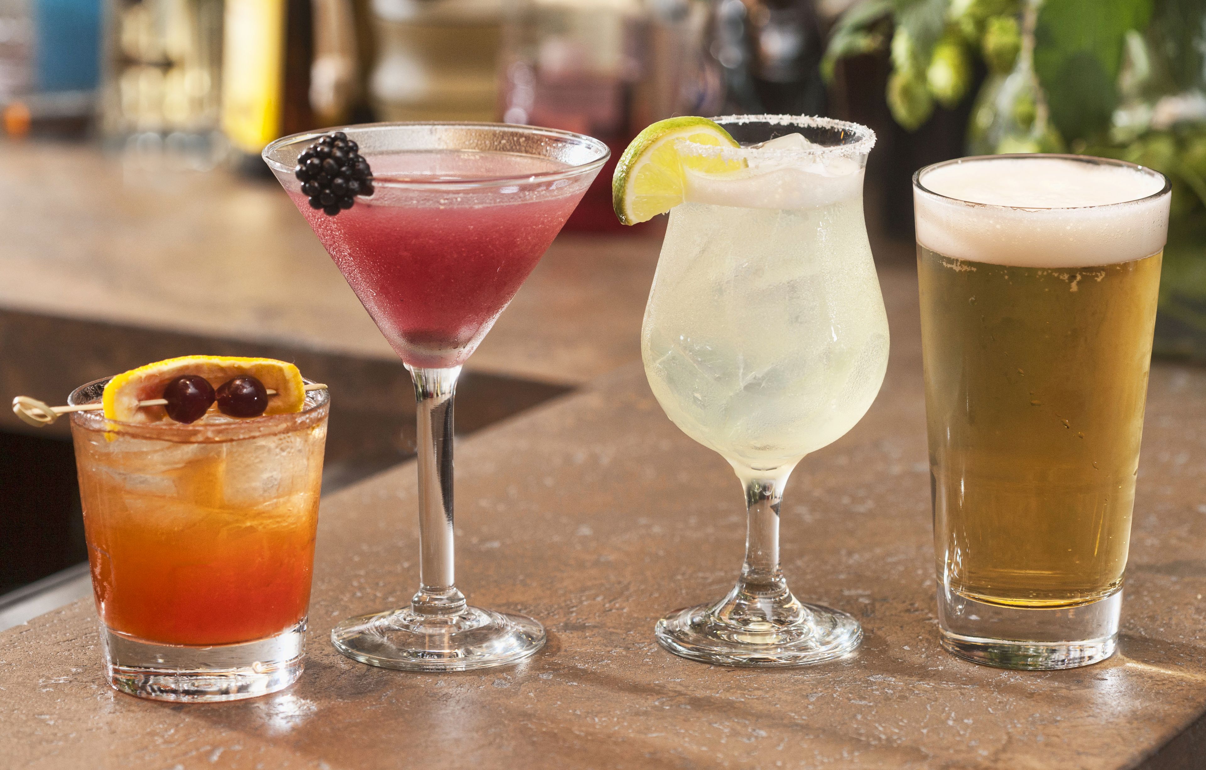 Four different types of drinks on a bar counter.
