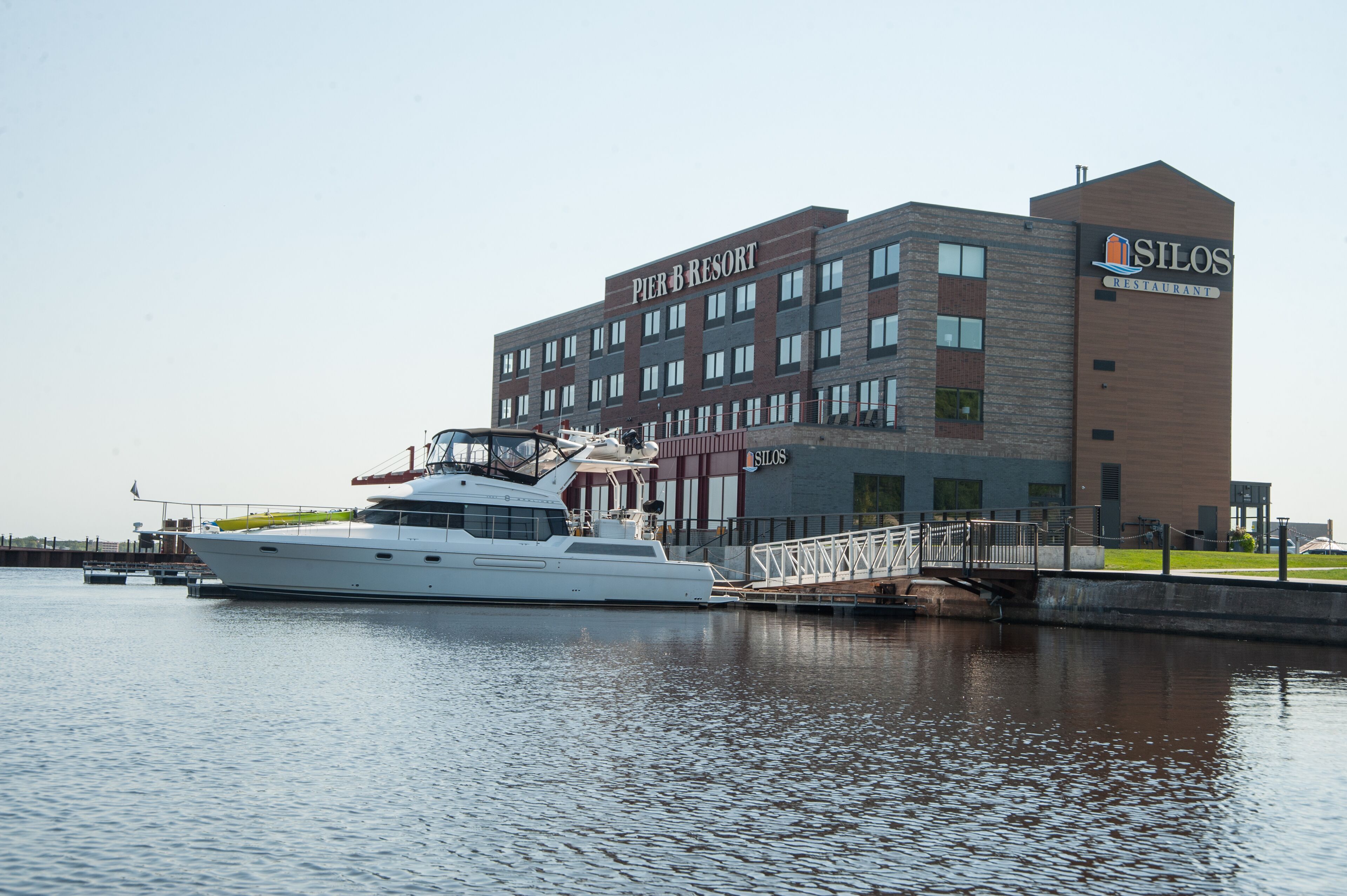 A large yacht docked at Pier 3 Resort, with a modern building featuring a restaurant named Silos.