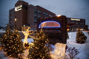 A hotel sign with illuminated lights, surrounded by snow and Christmas trees.