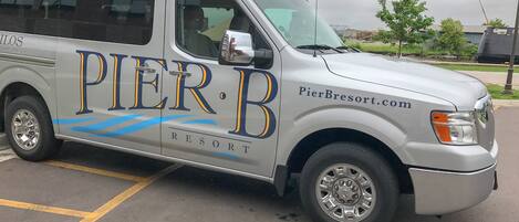 A silver van with 'PierBresort.com' branding, parked in a lot.