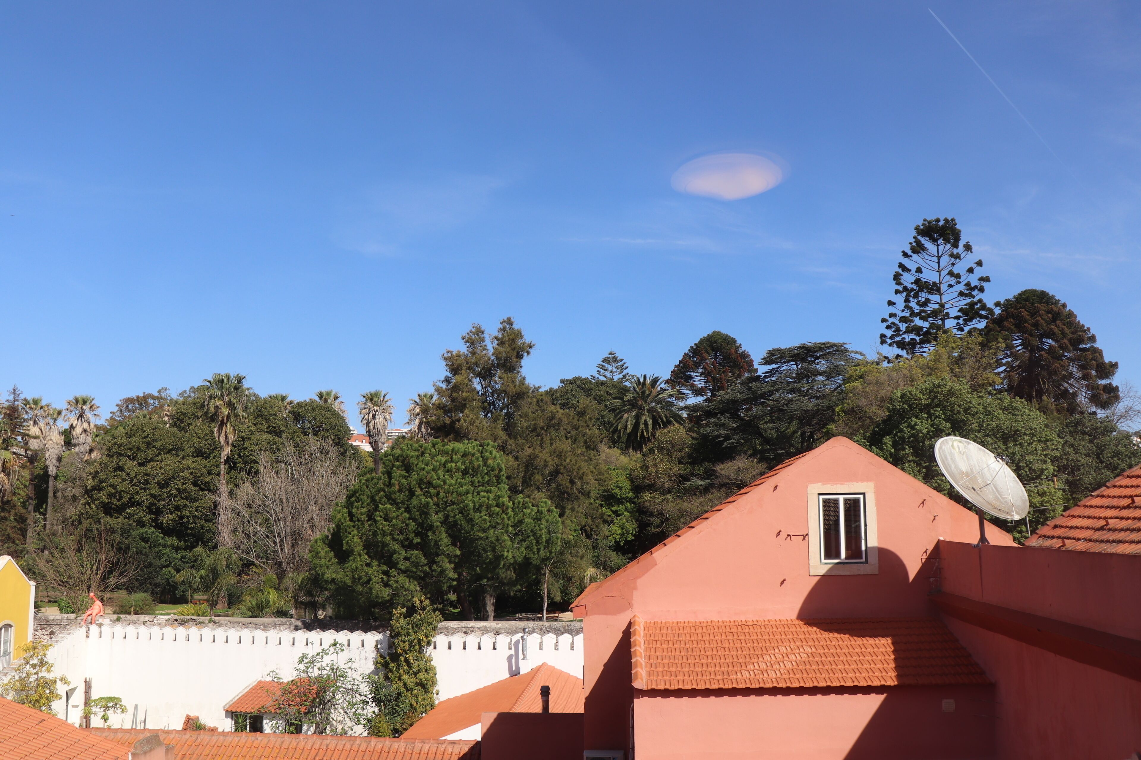 A residential area with houses featuring red-tiled roofs and a satellite dish.