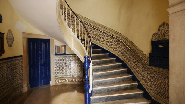 A staircase with ornate blue and gold railings, a blue door, and patterned tile walls. - Belém Tejo - Setubalense (Lisbon)