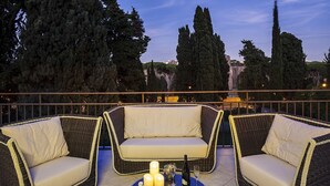 A terrace with wicker furniture and candles, overlooking a cityscape. - Pepoli9 Design Suites in Rome (Rome)