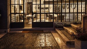 A warmly lit interior space with a patterned wall, a dining area with chairs and a table, and a staircase leading to an upper level. - Pepoli9 Design Suites in Rome (Rome)