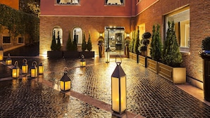 A hotel entrance with a brick facade, a wet cobblestone courtyard, and multiple lit lanterns. - Pepoli9 Design Suites in Rome (Rome)