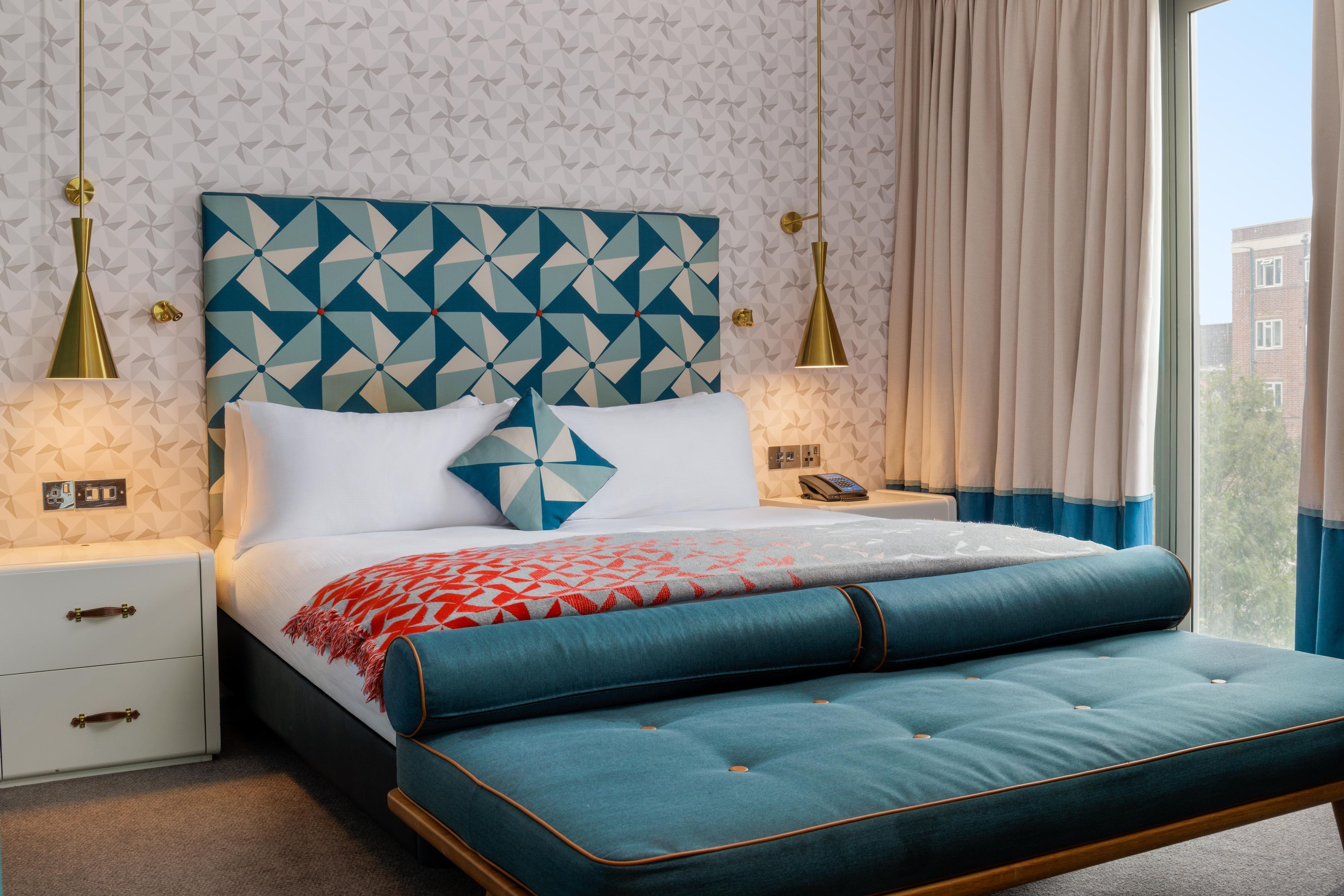 A hotel room with a bed, nightstands, a telephone, and a window with curtains.