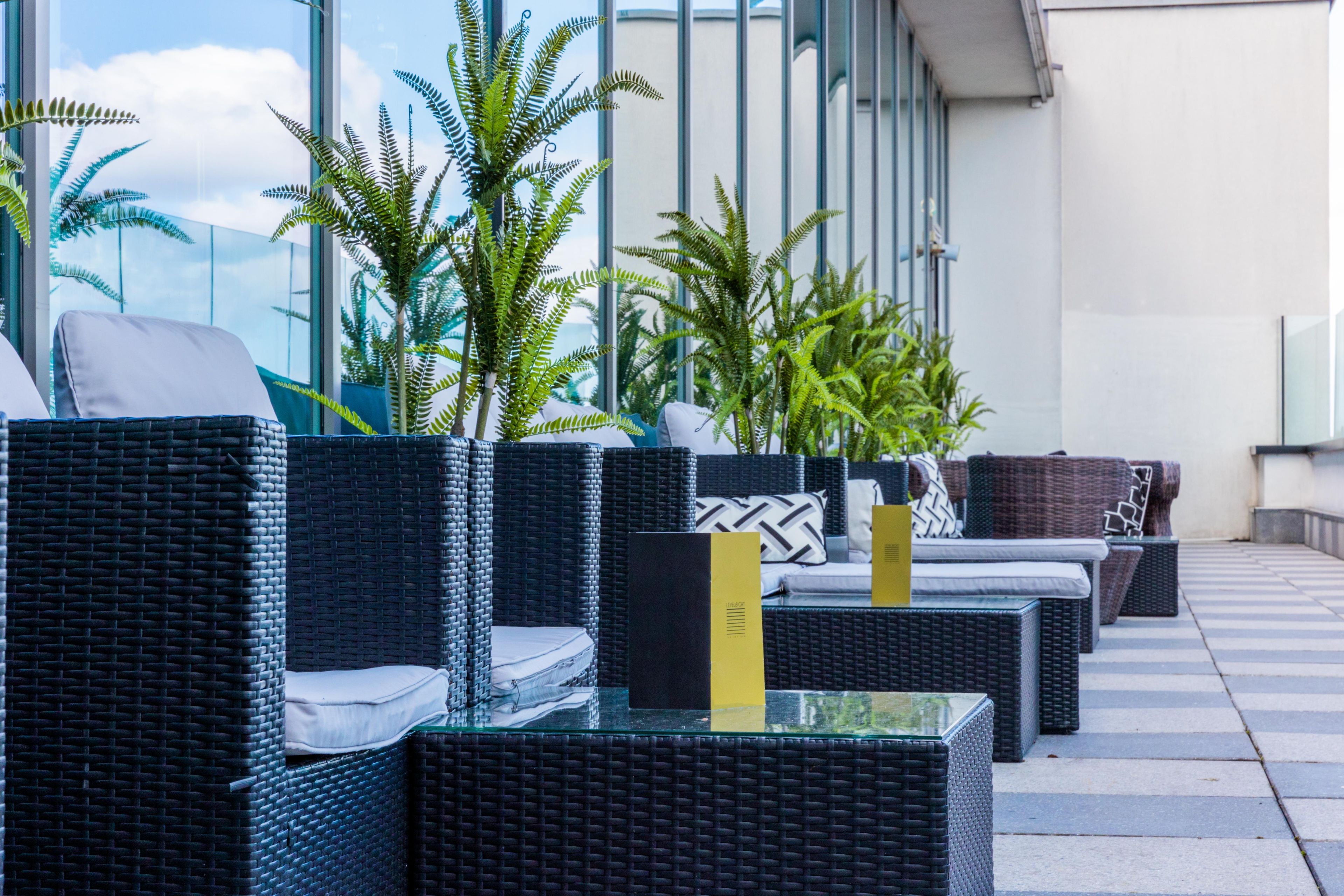 Outdoor wicker furniture with cushions, a glass table, and potted plants.