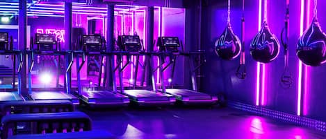 A gym with treadmills and weight machines, neon lighting, and a clean, modern design.