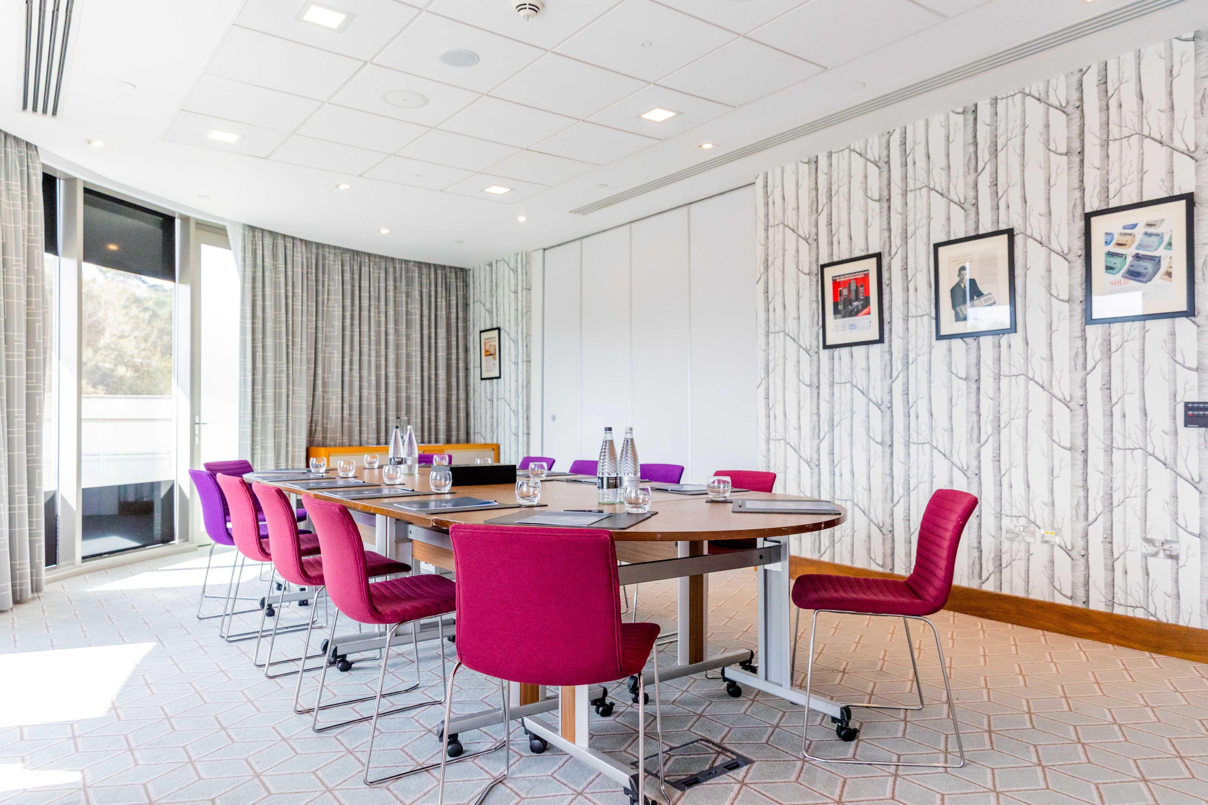 A conference room with a long table, purple chairs, and a whiteboard.