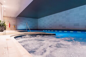 Un área de hidromasaje con un muro de azulejos y una piscina al fondo.