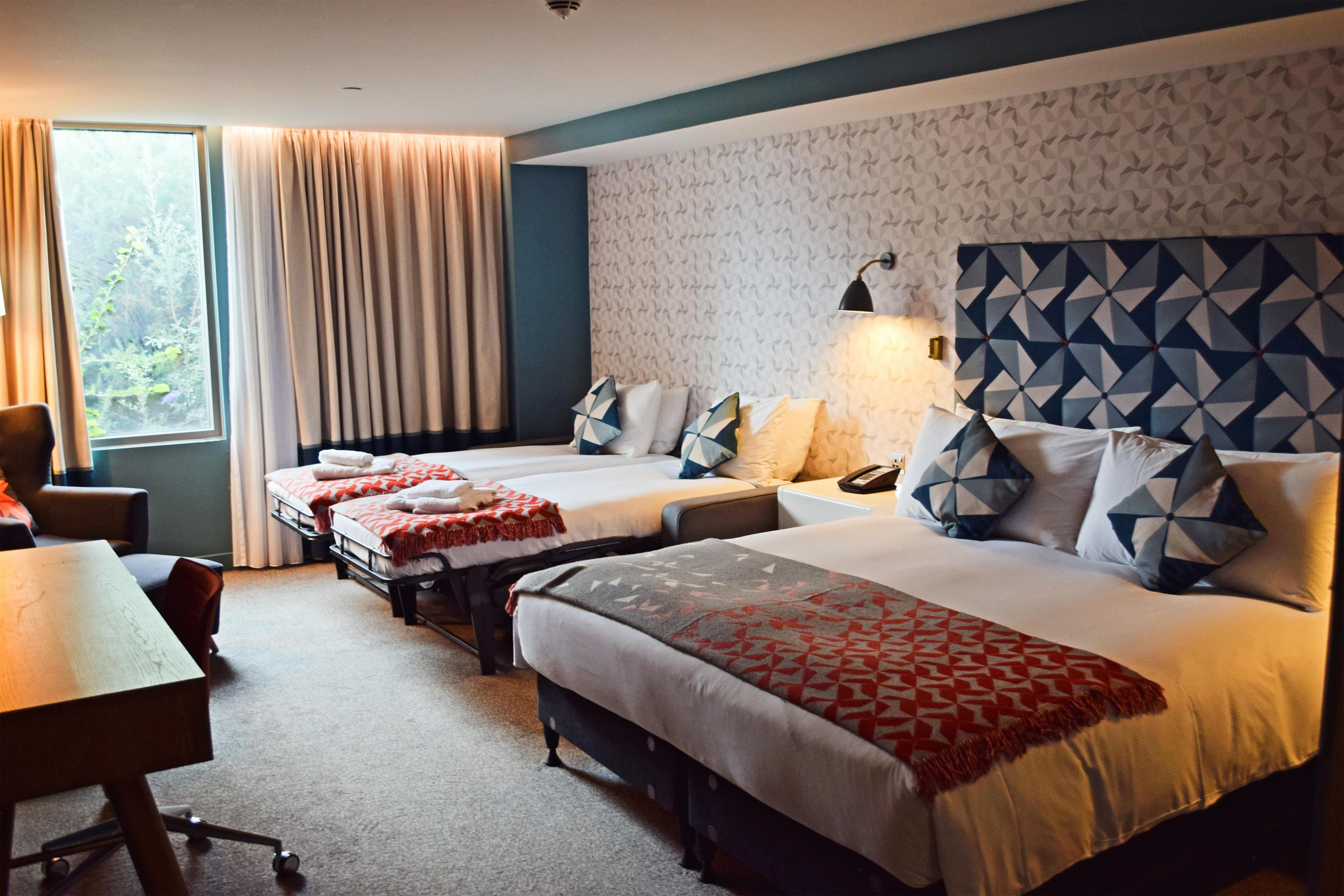 A hotel room with two beds, a desk, and a chair.