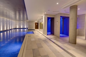 A modern indoor swimming pool area with a clear water surface, tiled walls, and a tiled floor. - Hilton Bournemouth (Bournemouth)