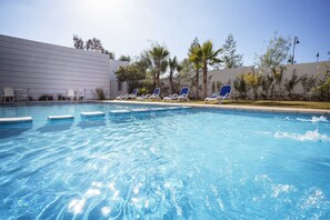Una piscina al aire libre, sillones reclinables de piscina