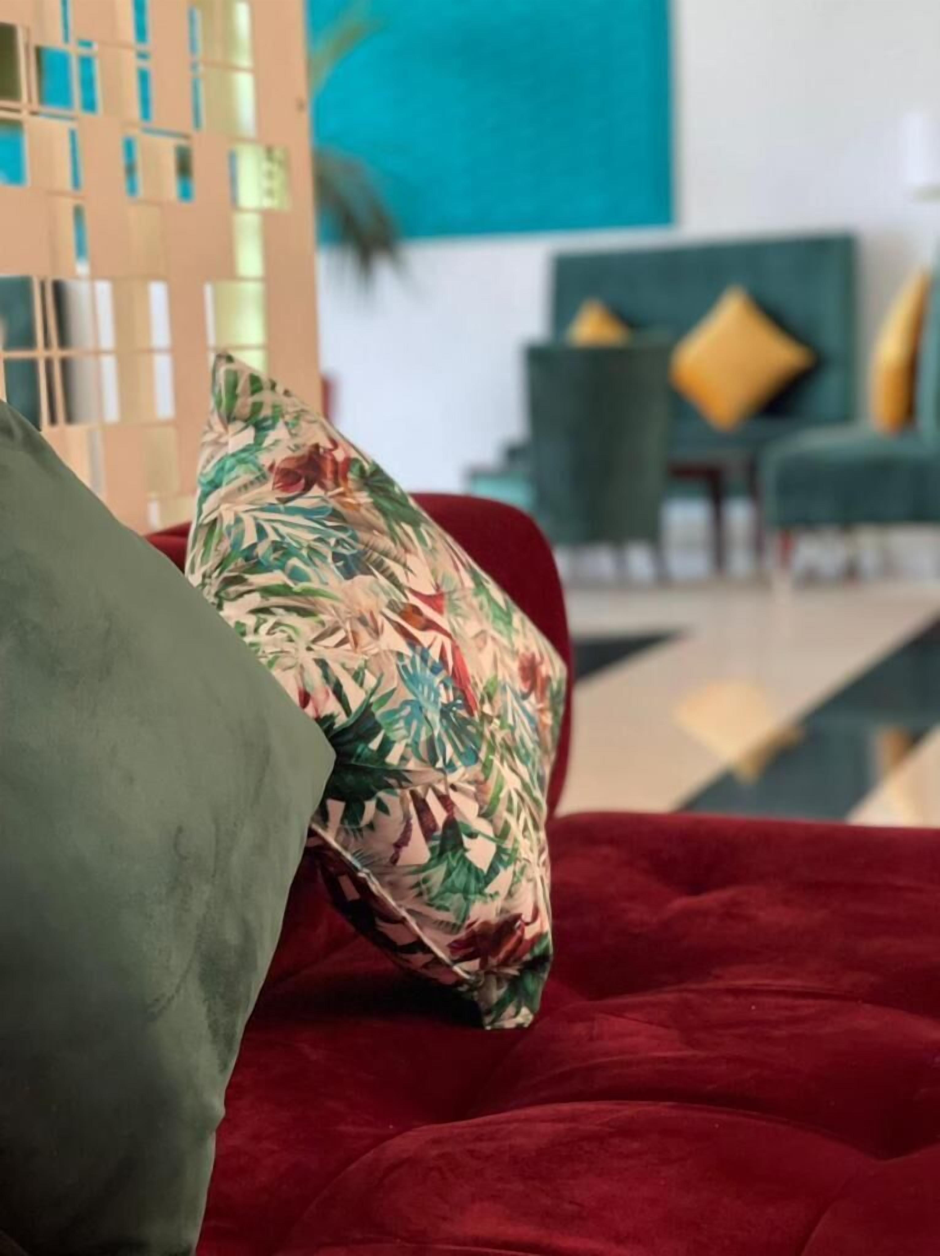 Un sofá rojo con un cojín floral y uno verde.