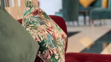 Un sofá rojo con un cojín floral y uno verde.