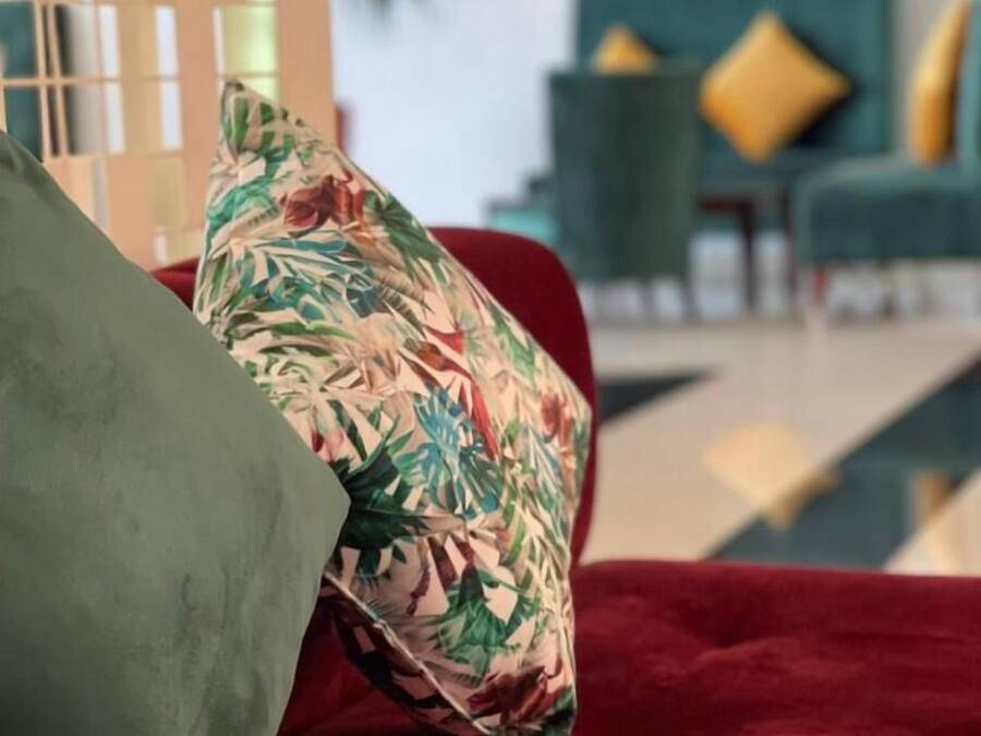 Un sofá rojo con un cojín floral y uno verde.
