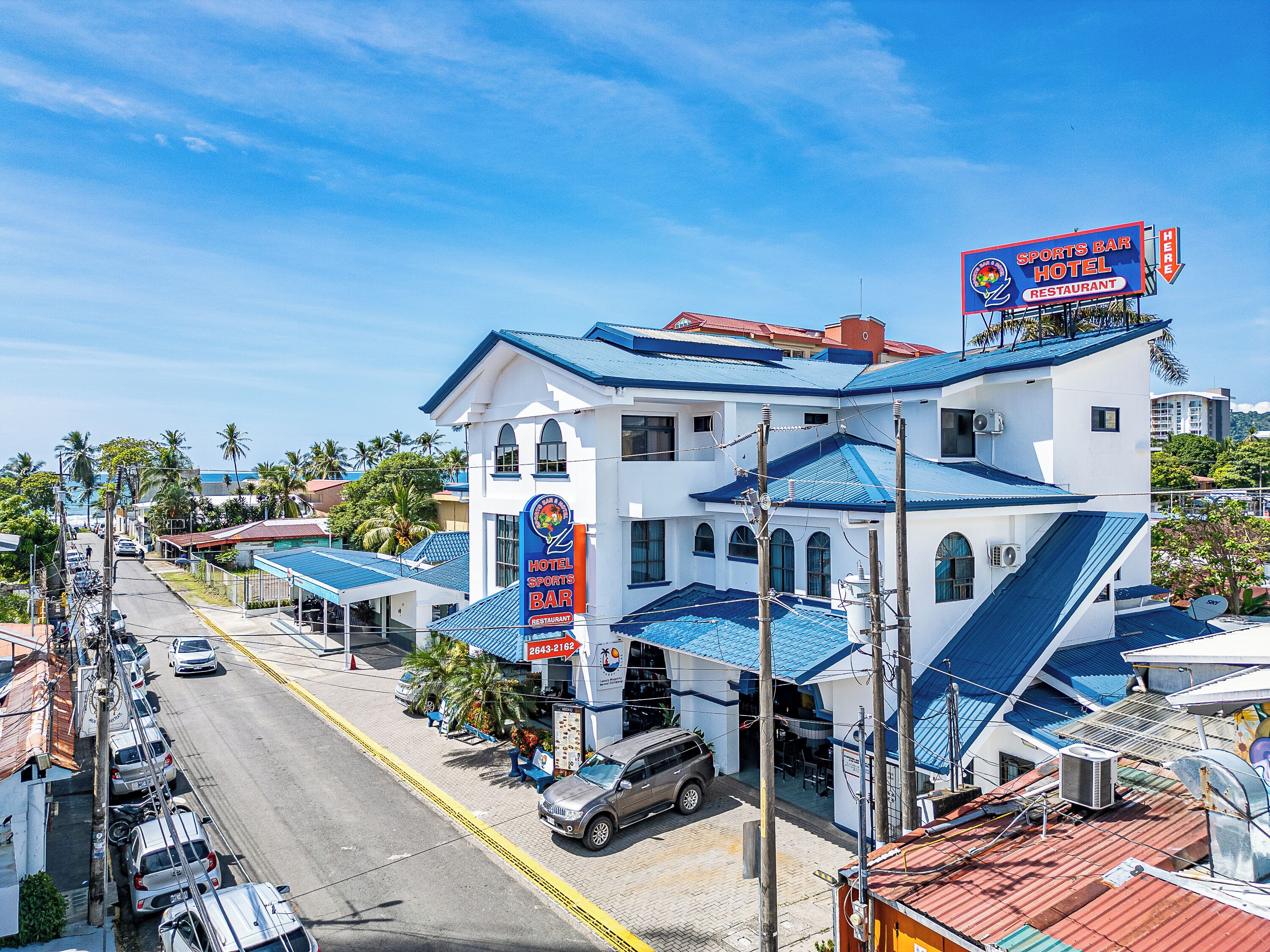 A hotel with a sports bar and restaurant, featuring a blue roof and white walls.