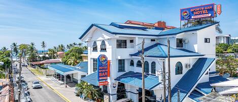 A hotel with a sports bar and restaurant, featuring a blue roof and white walls.