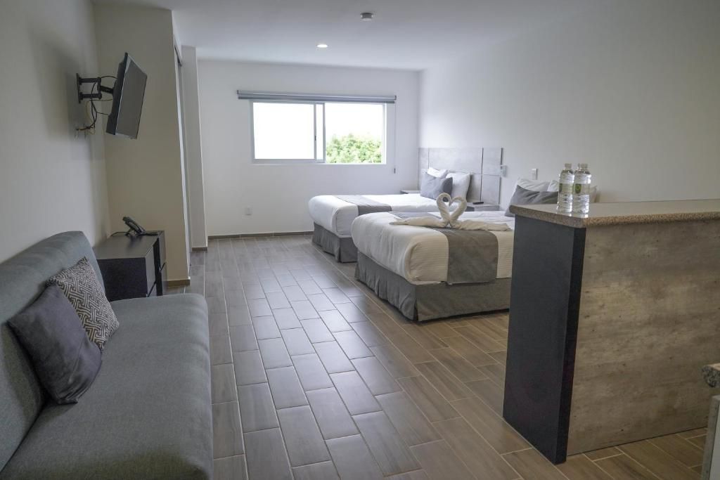 Une chambre d’hôtel avec un canapé, un lit décoré d’un motif en forme de cœur, un bureau et une fenêtre donnant sur un paysage verdoyant.