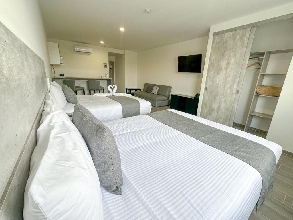 Una habitación de hotel con dos camas, un sofá, un televisor y un armario.