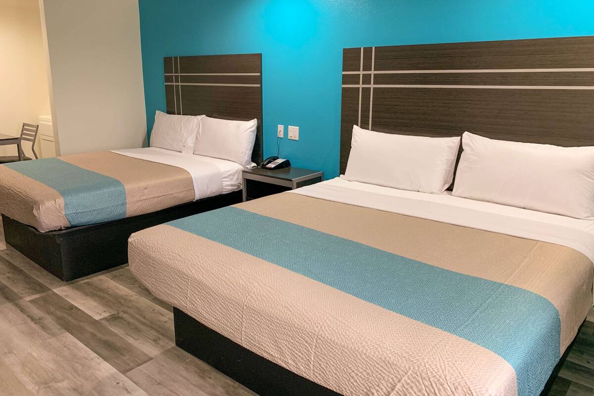 A hotel room with two beds, each with a headboard and a bedside table.
