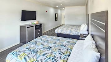 A hotel room with two beds, a TV, a desk, and a wardrobe.
